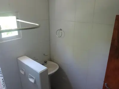 a white bathroom with a toilet and a sink at Cabaña Calamuchita Rumipal in Villa Rumipal