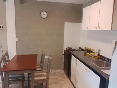 a kitchen with a table and a clock on the wall at Cabaña Calamuchita Rumipal in Villa Rumipal