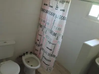 a bathroom with a toilet and a shower curtain at Cabaña Calamuchita Rumipal in Villa Rumipal