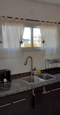 a kitchen counter with a sink and two windows at Departamento zona estadio Kempes in Cordoba