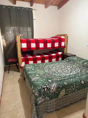 a bedroom with a bed with a green and red blanket at Nuevo complejo Clarita in Villa Carlos Paz