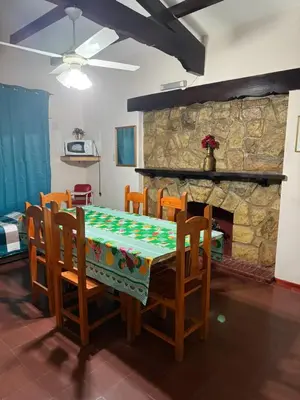 a dining room with a table and chairs and a stone fireplace at Nuevo complejo Clarita in Villa Carlos Paz