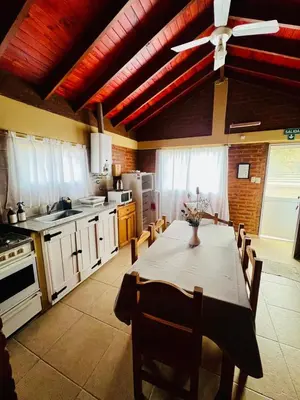 a kitchen with a table and a ceiling fan at Cabañas Los Tinos in Carpintería