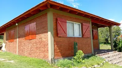 a small brick house with red doors and a window at canchu 11 in Arroyo de Los Patos