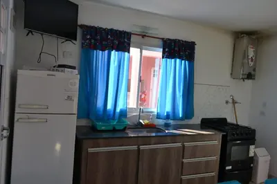 a kitchen with blue curtains and a sink and a refrigerator at Complejo Las Liebres in San Lorenzo