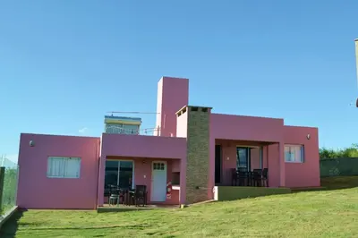 a pink house with chairs in a yard at Complejo Las Liebres in San Lorenzo