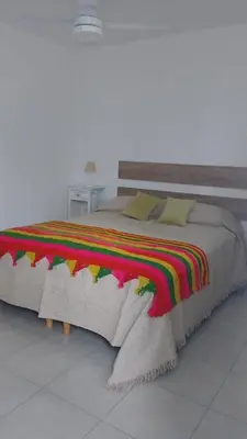 a large bed with a colorful blanket on it at Posada La Pedrera in Villa Yacanto
