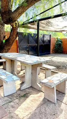 a picnic table and two benches sitting under a tree at La cantata in Merlo