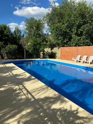 a blue swimming pool with two white chairs next to it at La cantata in Merlo