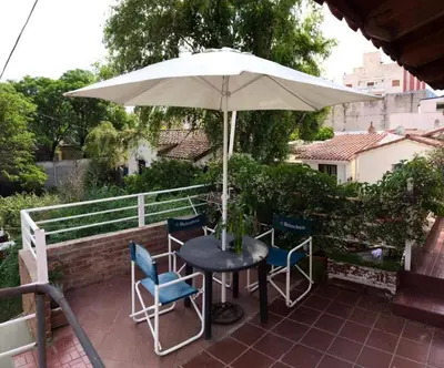 a table and chairs under an umbrella on a patio at Alquiler Temporario a una cuadra del reloj cucu in Villa Carlos Paz