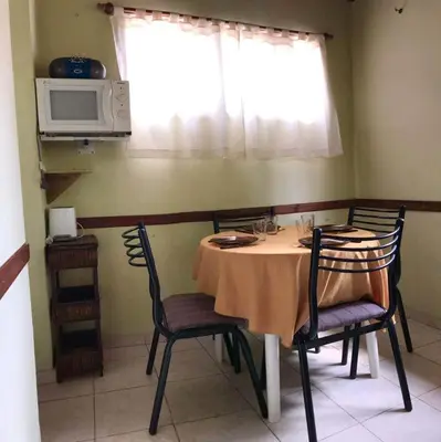 a dining room with a table with chairs and a microwave at Alquiler Temporario a una cuadra del reloj cucu in Villa Carlos Paz
