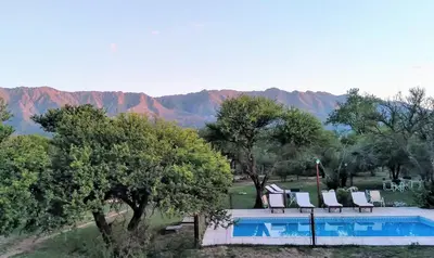 a swimming pool with chairs and mountains in the background at Cabañas Llajta Sumaj in Las Calles