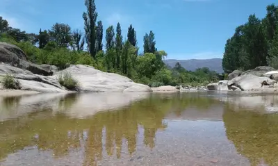a river with rocks and trees in the background at Cabañas Llajta Sumaj in Las Calles