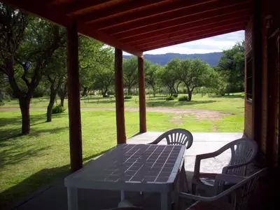 a picnic table and chairs on a porch with a view at Cabañas Llajta Sumaj in Las Calles