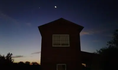 a building with a window and the moon in the sky at Cabañas Llajta Sumaj in Las Calles