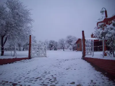 a fence covered in snow next to a house at Cabañas Llajta Sumaj in Las Calles