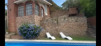 a house with a stone wall next to a swimming pool at Casa para 9 personas en Villa Carlos Paz in Villa Carlos Paz