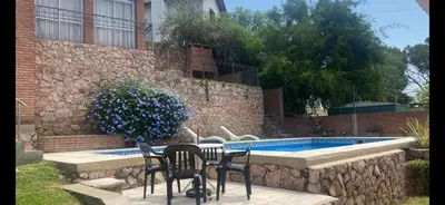 a table and chairs next to a swimming pool at Casa para 9 personas en Villa Carlos Paz in Villa Carlos Paz