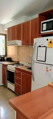 a kitchen with a white refrigerator and wooden cabinets at Nórdico Nueva Córdoba in Cordoba