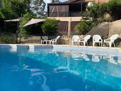 a swimming pool with white chairs and an umbrella at Departamento Vivaldi in Villa Carlos Paz