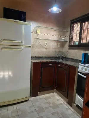 a kitchen with a white refrigerator and wooden cabinets at Departamento Vivaldi in Villa Carlos Paz
