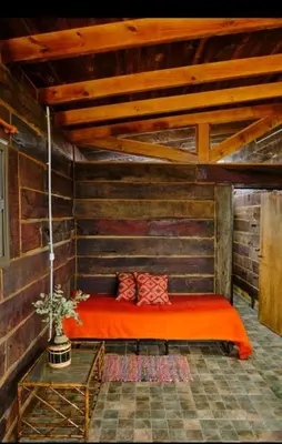 a bedroom with an orange bed in a room with wooden walls at Naturaleza Serrana in La Estancia