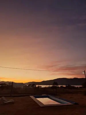 a pool in a field with a sunset in the background at Naturaleza Serrana in La Estancia