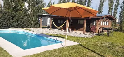 a pool with an umbrella next to a house at Naturaleza Serrana in La Estancia