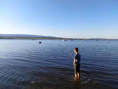 a man standing in the water holding a fishing rod at Cabaña La Linda in Villa General Belgrano