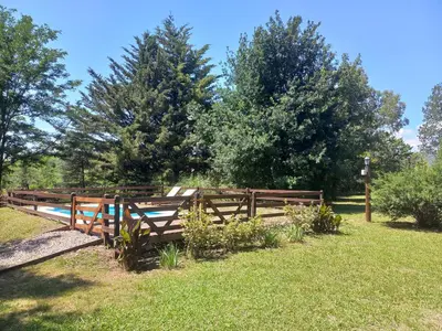a wooden fence in a field with trees at Cabaña La Linda in Villa General Belgrano