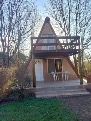 a small house with a porch and a table at Cabaña La Linda in Villa General Belgrano