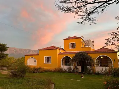 a yellow house with a rainbow in the sky at La casona del rio in Nono
