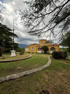 a yellow house with a stone path in a yard at La casona del rio in Nono
