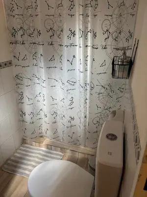 a bathroom with a toilet and a shower curtain with writing at Depto 24 en Barrio Villa Belgrano excelente ubicación in Cordoba