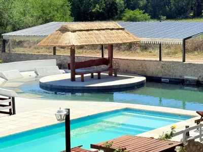 a chair under an umbrella next to a swimming pool at Valle Serrano in Mina Clavero
