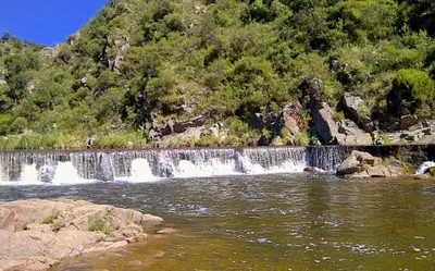 a river with a waterfall in front of a mountain at Valle Serrano in Mina Clavero