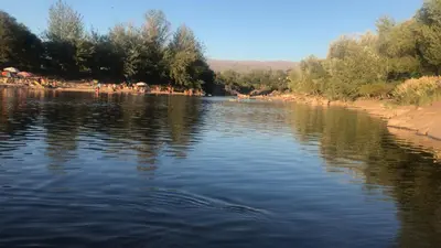 a river with a group of people on a beach at Valle Serrano in Mina Clavero