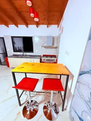 a kitchen with a wooden table and two red stools at Valle Serrano in Mina Clavero
