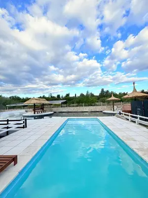 a swimming pool with blue water and umbrellas at Valle Serrano in Mina Clavero