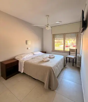 a bedroom with a bed and a chair and a window at Hotel Montecarlo PSH in Villa Carlos Paz
