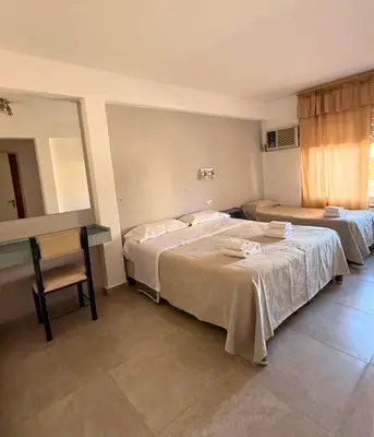 a bedroom with two beds and a desk and a window at Hotel Montecarlo PSH in Villa Carlos Paz