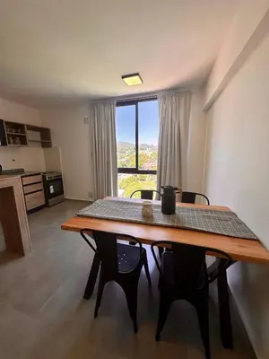 a room with a table with chairs and a large window at Depa a Estrenar en el Centro, Pile, Aire Ac in Villa Carlos Paz