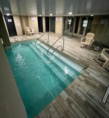 a large swimming pool in a building with chairs at Miralejos VII - Edificio Premium - Departamento 1 Dormitorio in Villa Carlos Paz