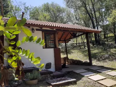 a small house with a wooden pavilion in a yard at Cabañas Franca Austral in Santa Rosa de Calamuchita