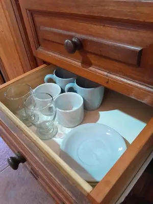 a drawer with bowls and dishes in a cabinet at Cabañas Franca Austral in Santa Rosa de Calamuchita