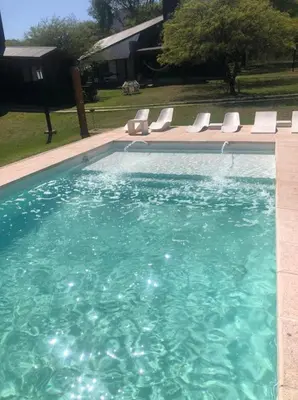 a swimming pool with lounge chairs and a swimming pool at LunaNegra Casas de descanso in Villa General Belgrano