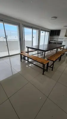 a table and benches in a room with a view of the ocean at Viamonte deluxe Barrio General Paz 2 dormitorios in Cordoba