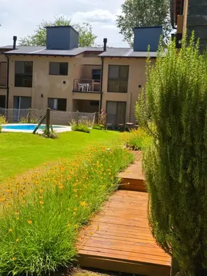 a garden with a wooden walkway in front of a building at FlussHaus3 in Villa General Belgrano