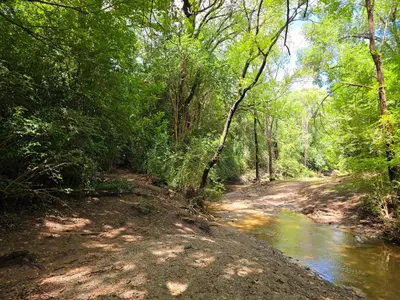 a dirt road next to a river with trees at FlussHaus3 in Villa General Belgrano
