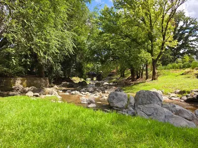 a river with rocks and trees in a field at FlussHaus3 in Villa General Belgrano